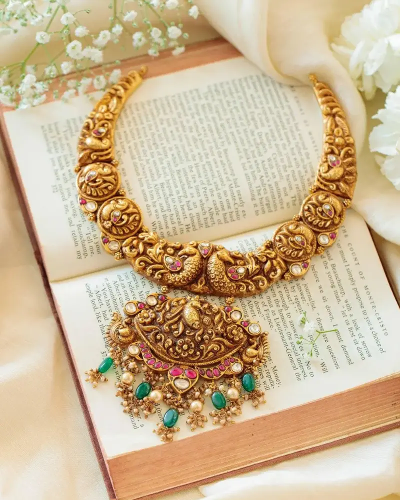 Premium antique temple jewellery necklace with matching earrings displayed on an elegant ivory marble stand.